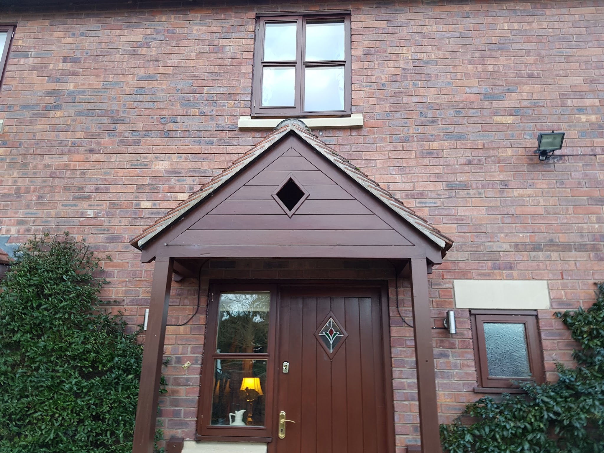 Brick house front with a freshly painted porch canopy and front door